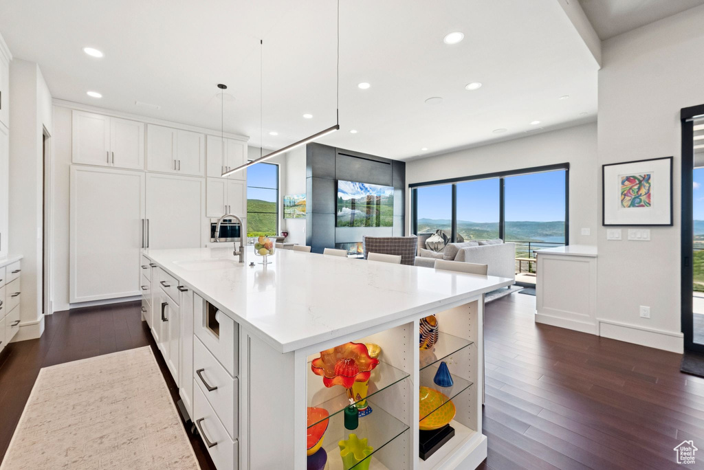 Kitchen featuring recessed lighting, white cabinets, open shelves, dark wood-type flooring, and light stone counters