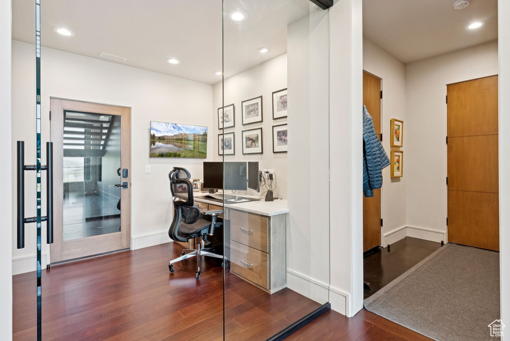 Home office with dark wood-type flooring and recessed lighting