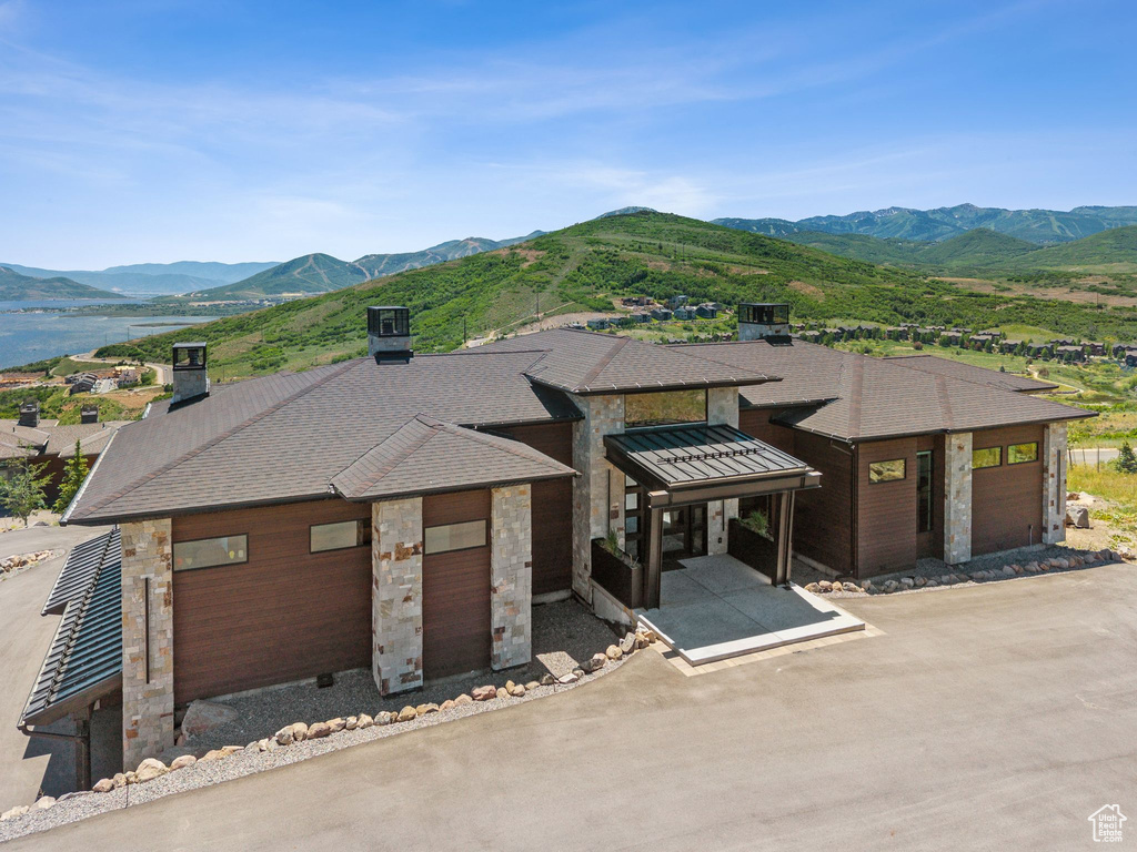 View of front of house featuring a mountain view, stone siding, and roof with shingles