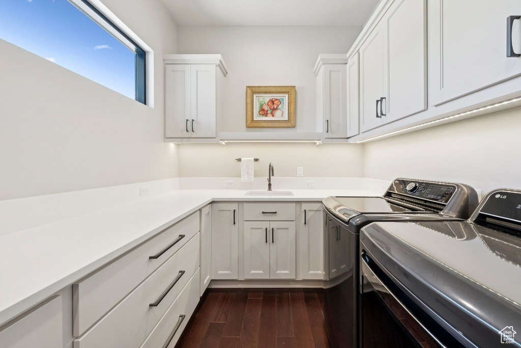 Laundry area with independent washer and dryer, dark wood-style floors, and cabinet space