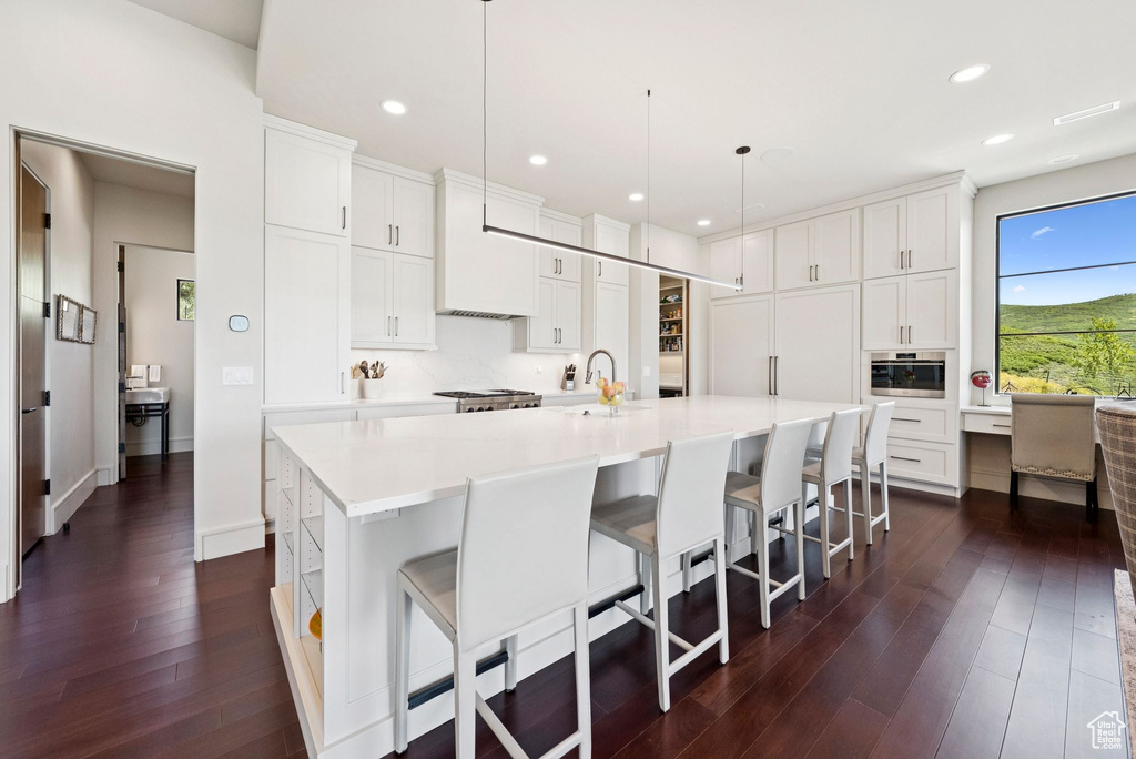 Kitchen with dark wood-style floors, light countertops, a large island, white cabinetry, and recessed lighting