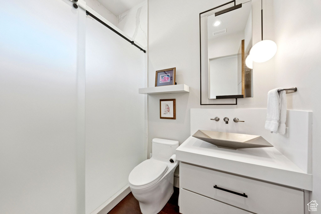 Full bathroom featuring vanity, a shower, and wood finished floors