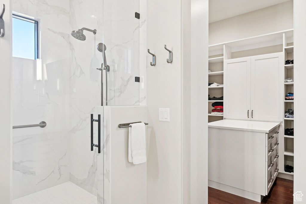 Full bath with a spacious closet, a marble finish shower, and wood finished floors