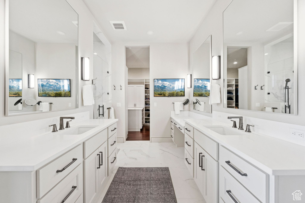 Bathroom with a walk in closet, two vanities, marble finish floors, a shower stall, and recessed lighting