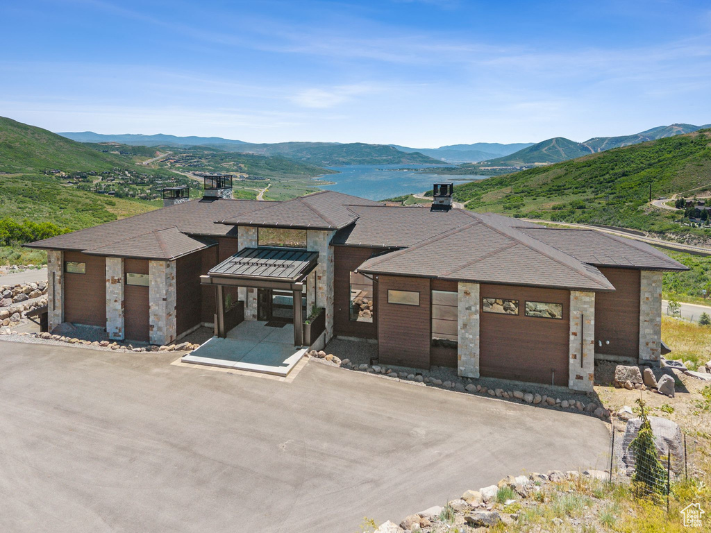 View of front of property featuring a mountain view, stone siding, brick siding, and a chimney