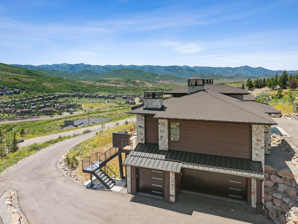 View of front of property featuring a standing seam roof, stone siding, a mountain view, and driveway