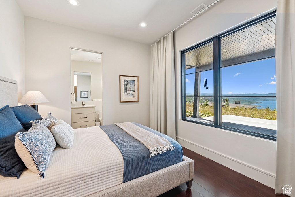 Bedroom with dark wood-style floors, recessed lighting, a water view, and ensuite bathroom