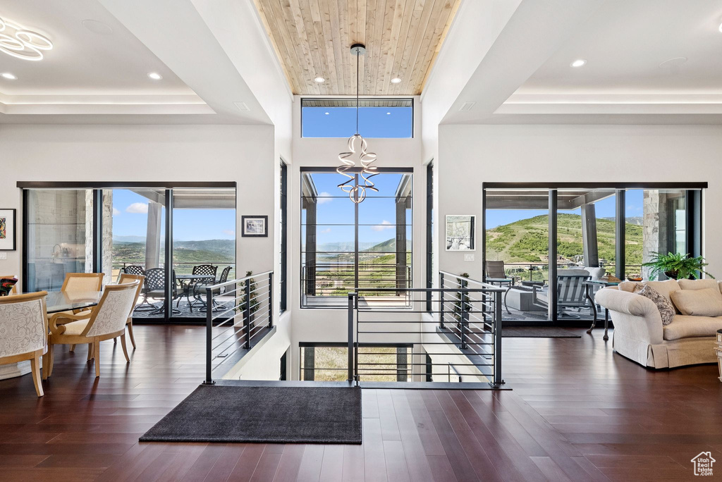 Entrance foyer with a tray ceiling, a chandelier, dark wood-style floors, recessed lighting, and a towering ceiling