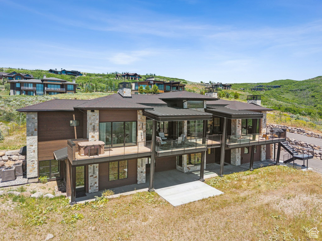 Rear view of house with stone siding, a standing seam roof, and a mountain view