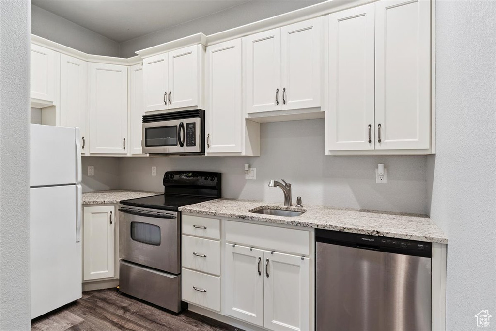 Kitchen with appliances with stainless steel finishes, dark wood-style flooring, and white cabinetry
