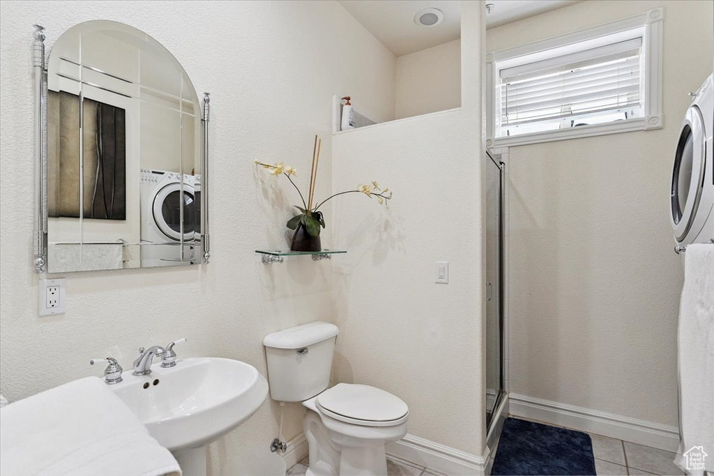 Full bath with tile patterned floors, an enclosed shower, and washer / dryer
