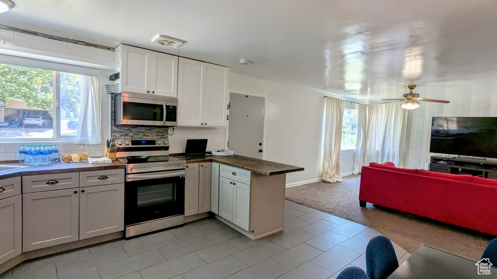 Kitchen with stainless steel appliances, a peninsula, open floor plan, dark countertops, and tasteful backsplash