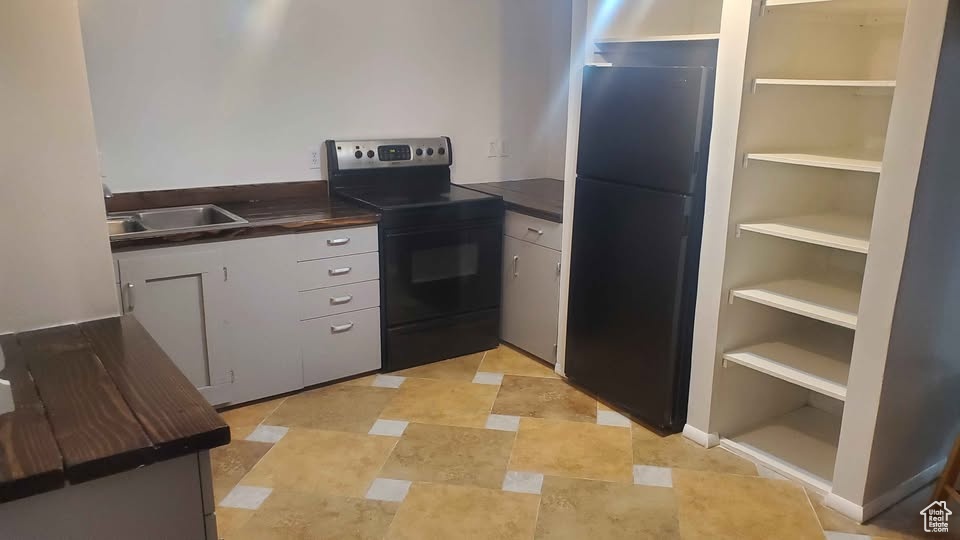 Kitchen with black appliances, dark countertops, and built in shelves