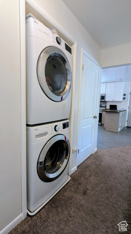 Laundry room with stacked washer and clothes dryer and light carpet