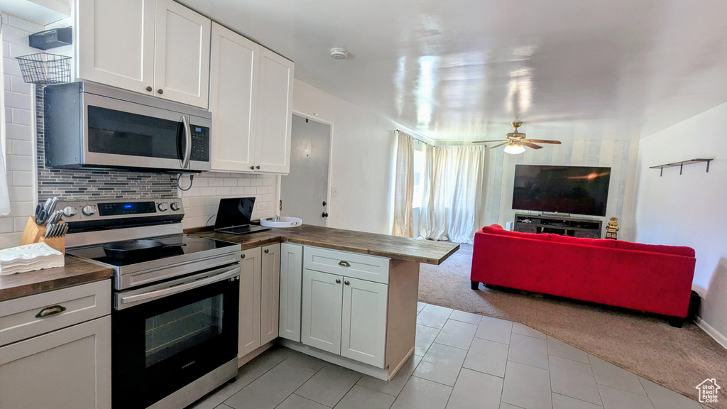 Kitchen with appliances with stainless steel finishes, light carpet, a peninsula, open floor plan, and butcher block countertops