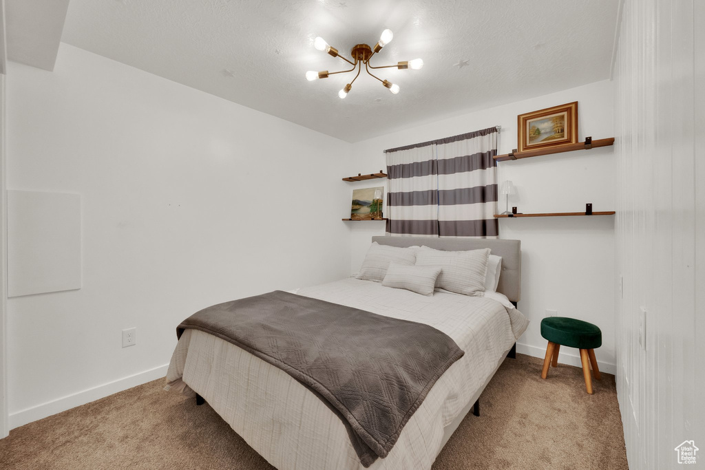 Carpeted bedroom with a chandelier and baseboards