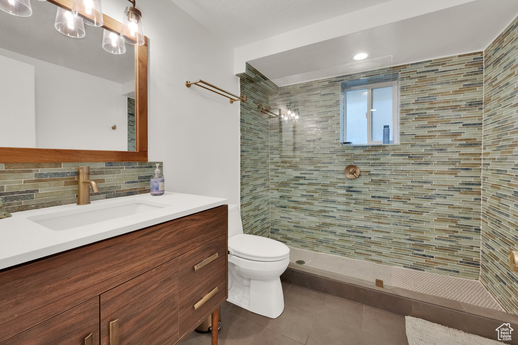 Bathroom with vanity, a tile shower, tile patterned flooring, tasteful backsplash, and recessed lighting