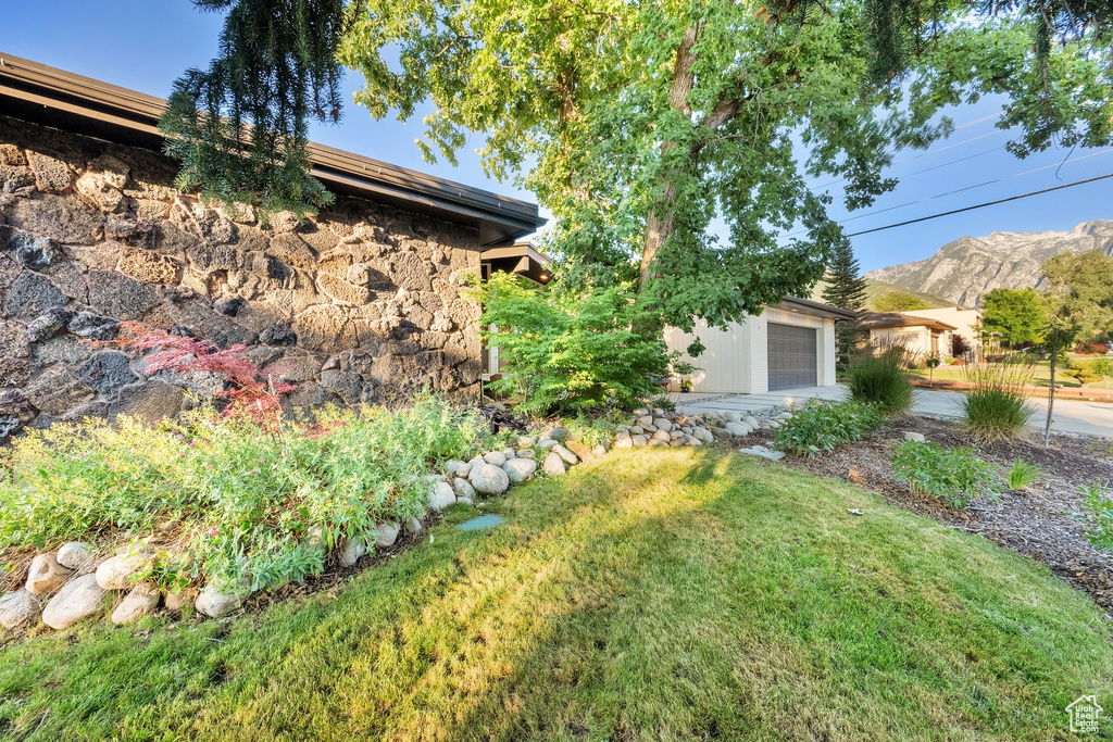 View of grassy yard featuring a mountain view and a garage