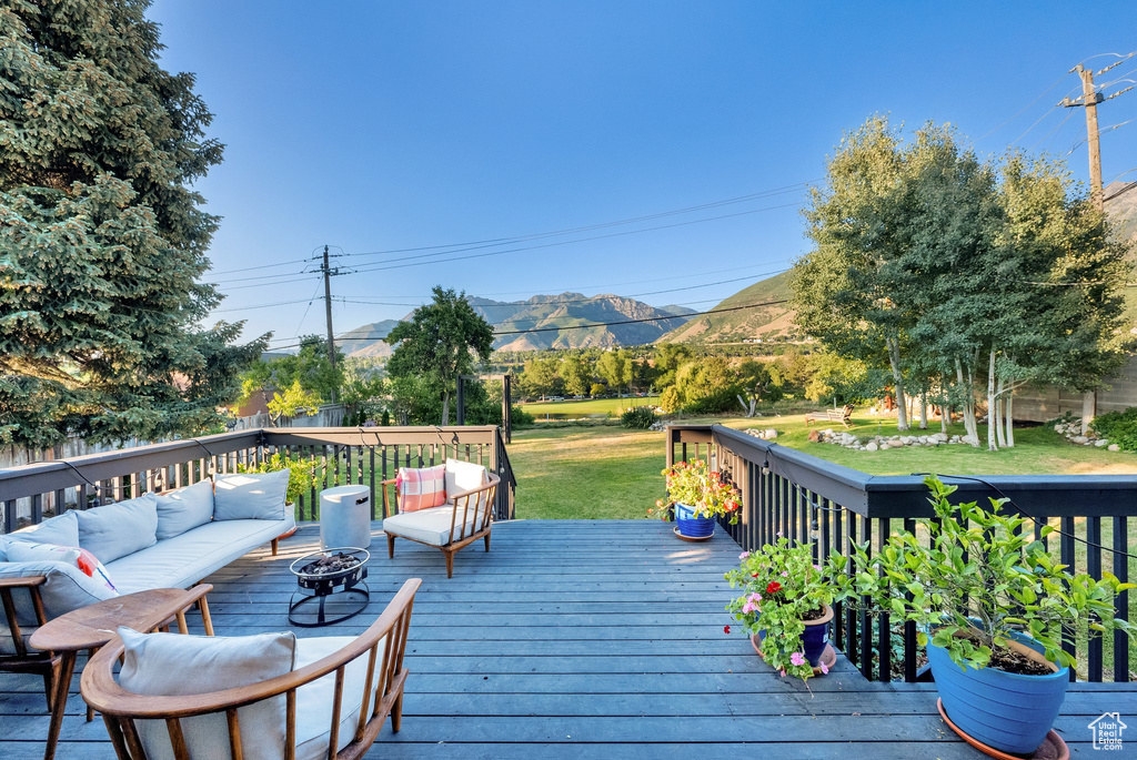 Deck with a mountain view, outdoor lounge area, and a lawn