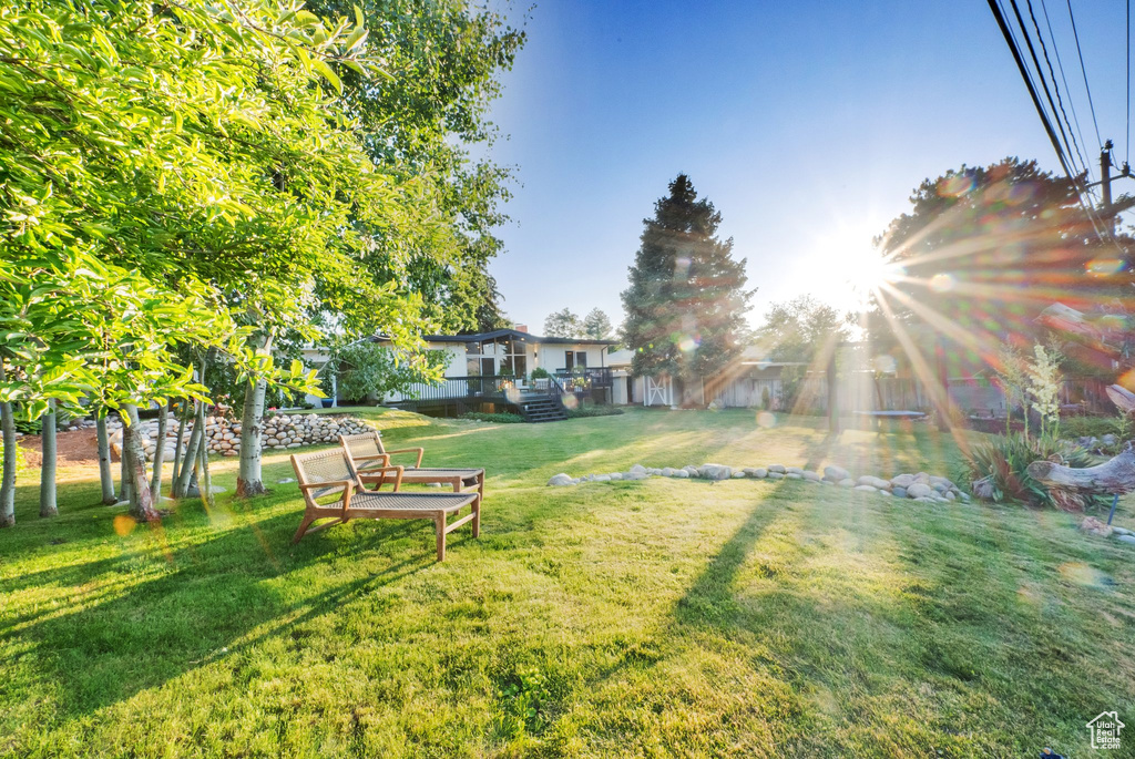 View of grassy yard featuring a wooden deck