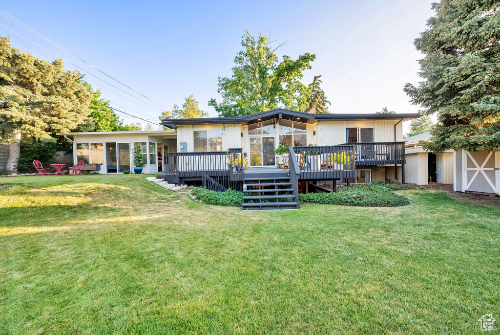 Back of house with a sunroom, stairway, a wooden deck, and a lawn
