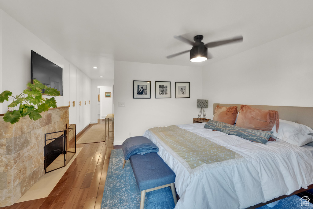 Bedroom with hardwood / wood-style floors, recessed lighting, ceiling fan, and a fireplace