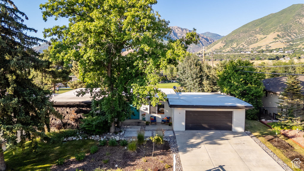 View of front of house featuring a mountain view, concrete driveway, an attached garage, and brick siding