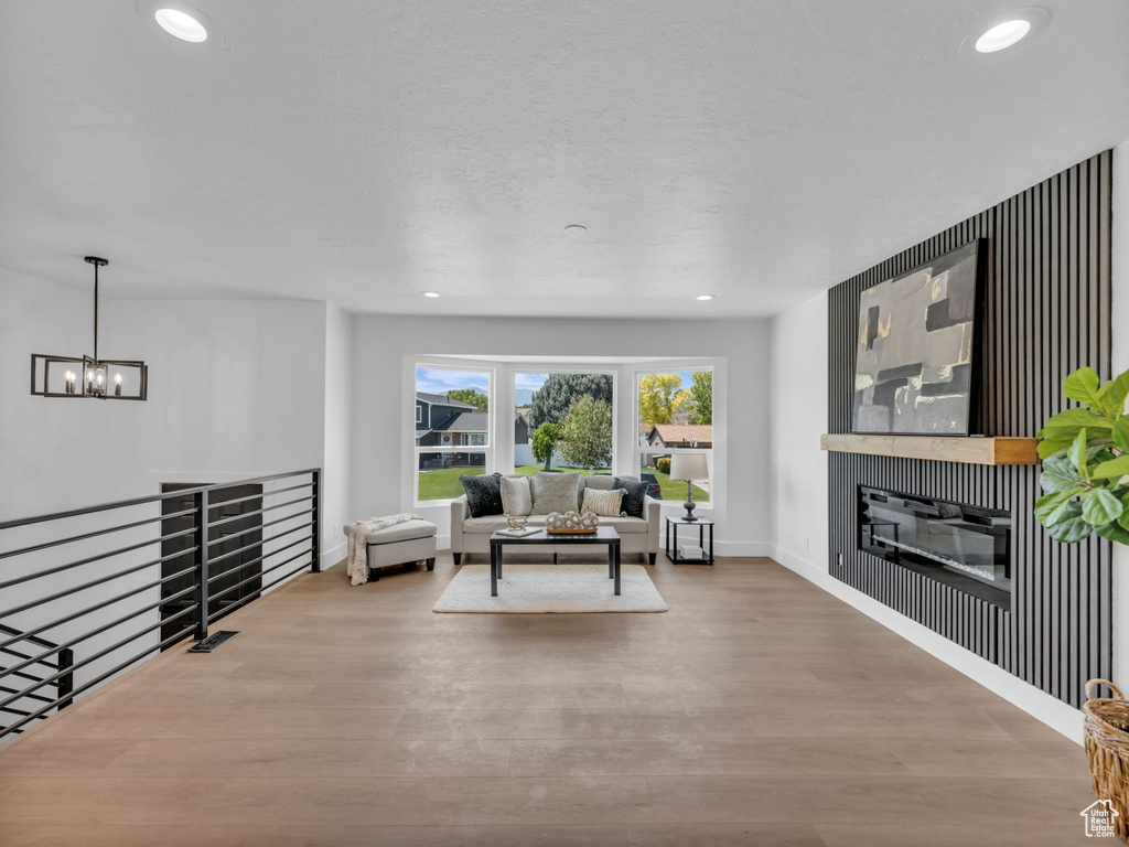Living area featuring wood finished floors, a chandelier, recessed lighting, and a glass covered fireplace