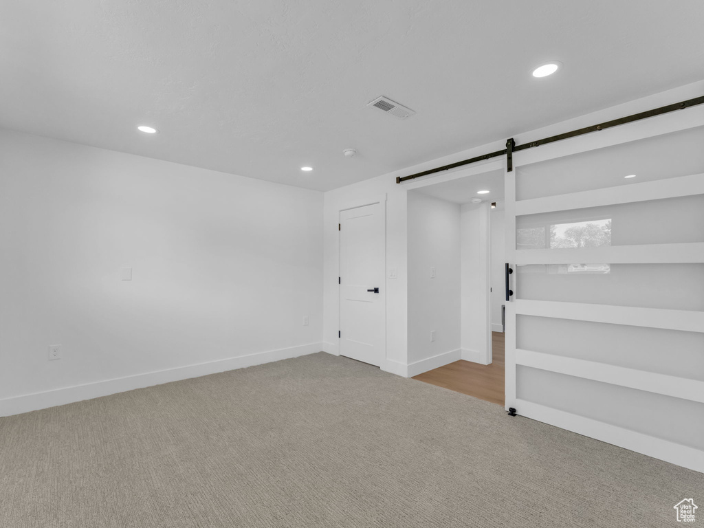 Basement featuring carpet floors, recessed lighting, and a barn door