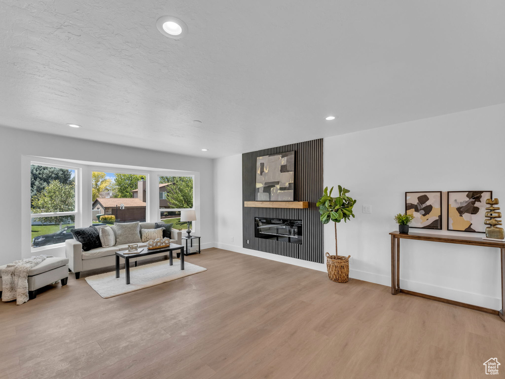 Living area featuring light wood-style floors, a glass covered fireplace, and recessed lighting
