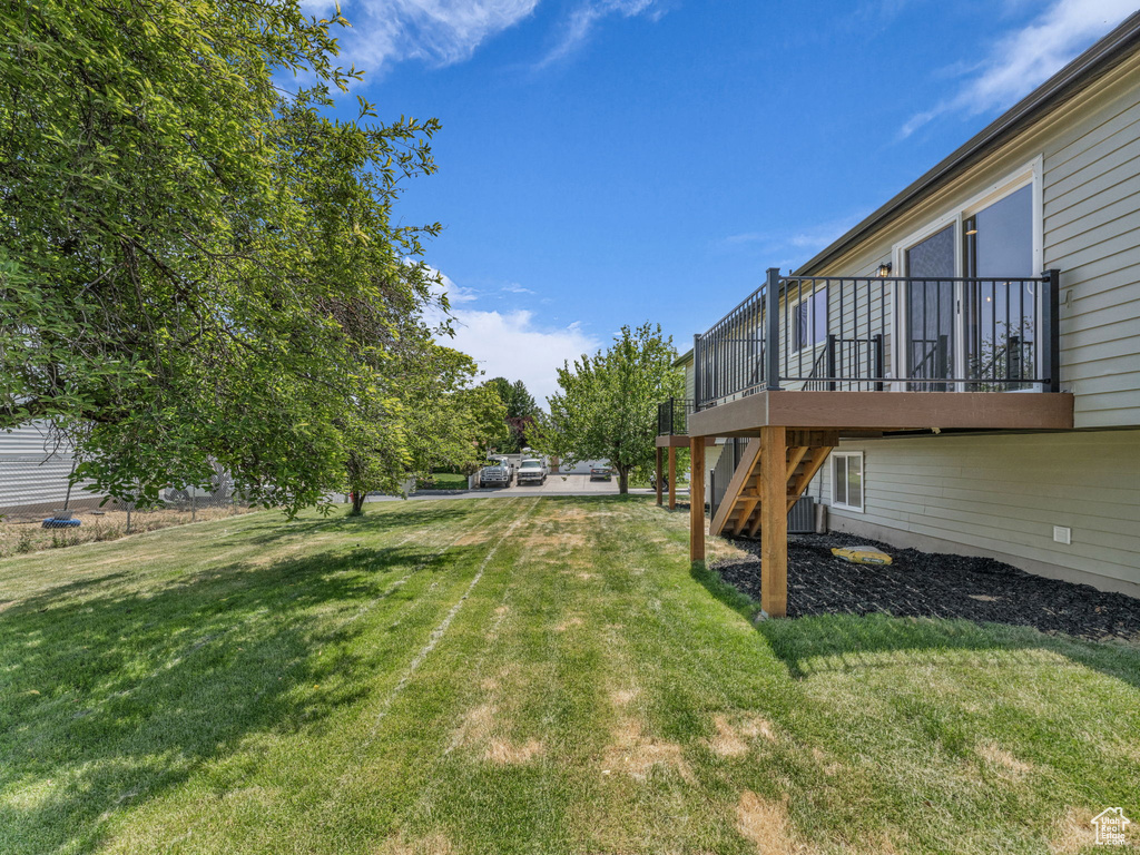 View of green lawn featuring stairway and a deck