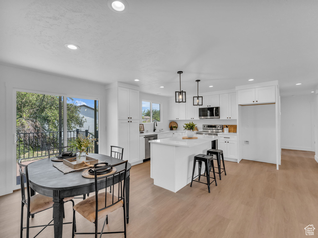 Kitchen featuring stainless steel appliances, recessed lighting, light wood finished floors, a kitchen island, and white cabinets