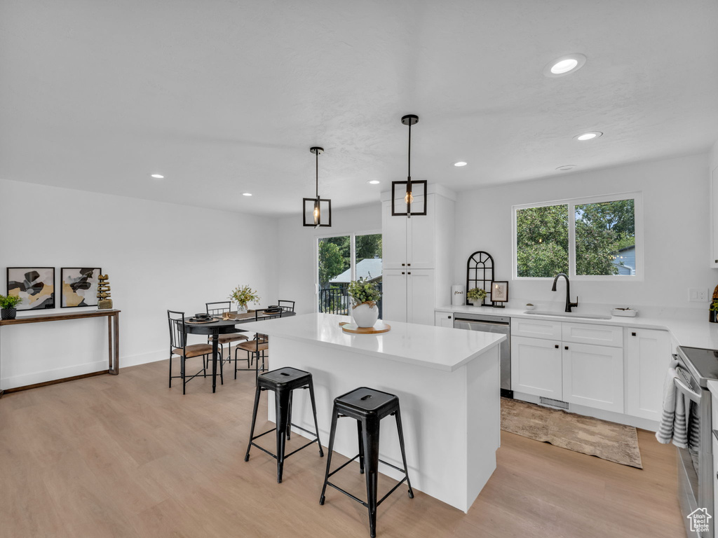 Kitchen featuring appliances with stainless steel finishes, light wood-type flooring, a kitchen breakfast bar, plenty of natural light, and recessed lighting