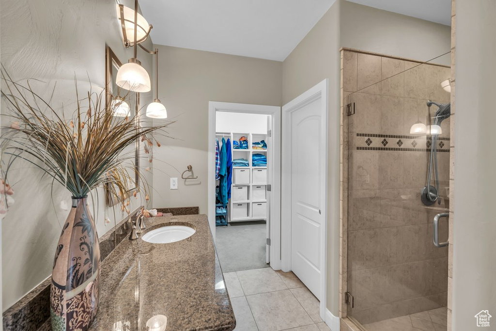 Full bathroom featuring a shower stall, vanity, a spacious closet, and tile patterned floors