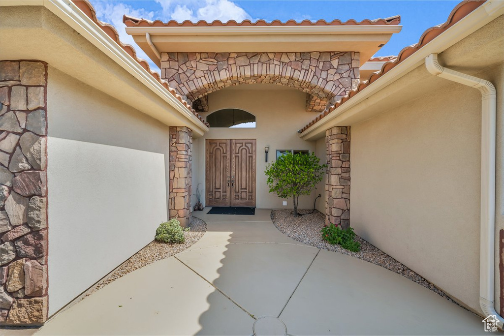 View of exterior entry featuring stone siding, a tile roof, and stucco siding