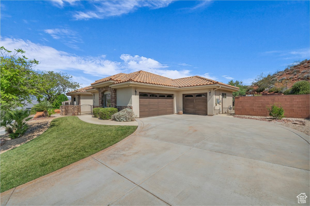 Mediterranean / spanish-style home featuring stone siding, stucco siding, a tile roof, a garage, and concrete driveway