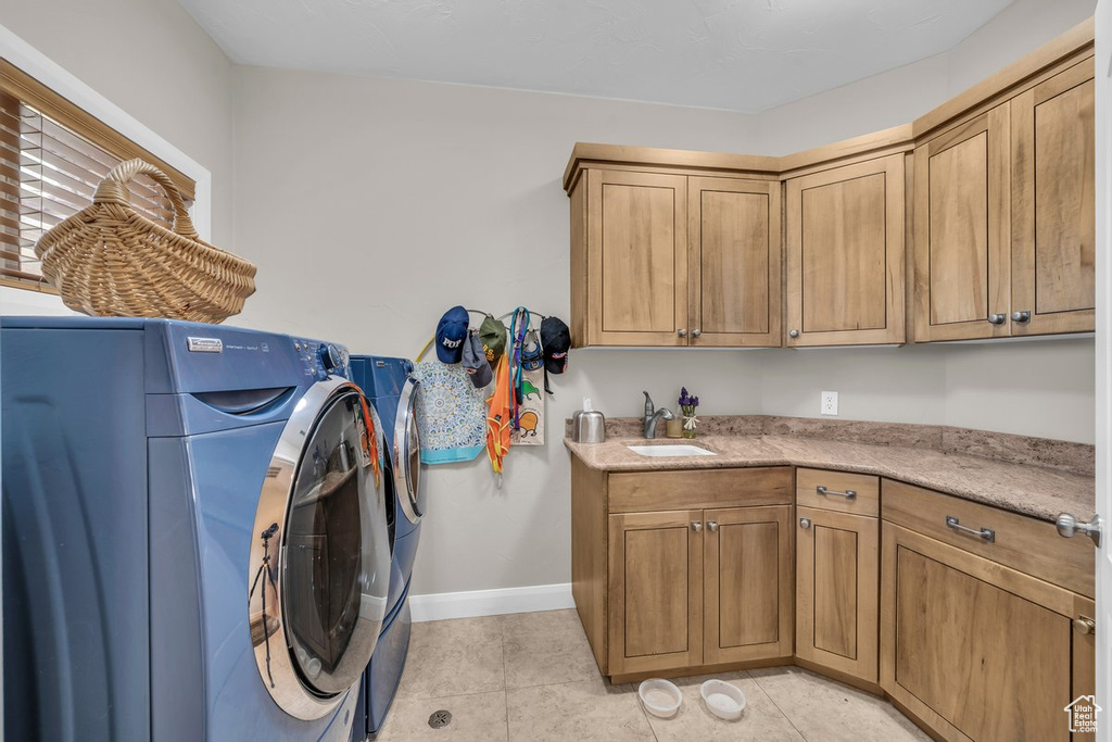 Laundry room with cabinet space, washing machine and dryer, and light tile patterned floors