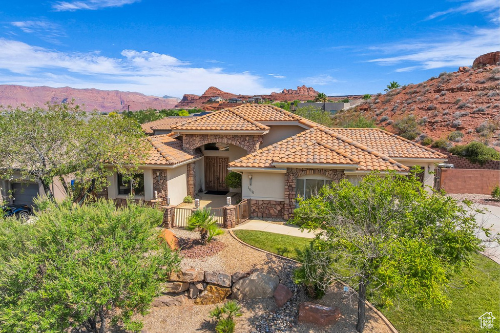 Mediterranean / spanish home featuring stucco siding, a tiled roof, stone siding, and a mountain view