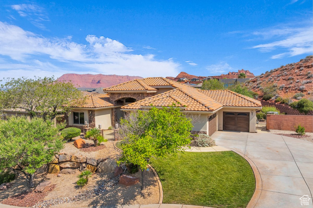 Mediterranean / spanish home with driveway, a tiled roof, a garage, a mountain view, and stucco siding
