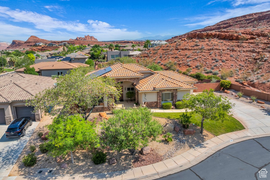 View of front of home with a tile roof, stucco siding, driveway, and roof mounted solar panels