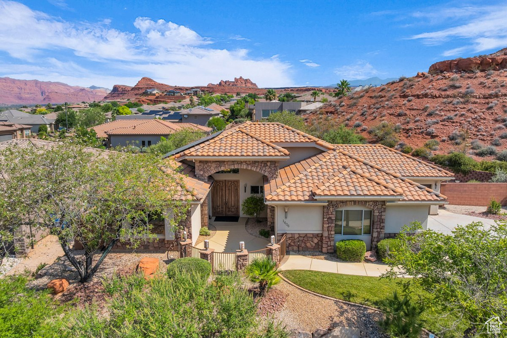 Mediterranean / spanish home featuring stucco siding, stone siding, a tile roof, and a mountain view
