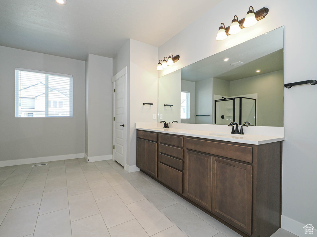 Bathroom with plenty of natural light, double vanity, a shower with shower door, tile patterned flooring, and recessed lighting