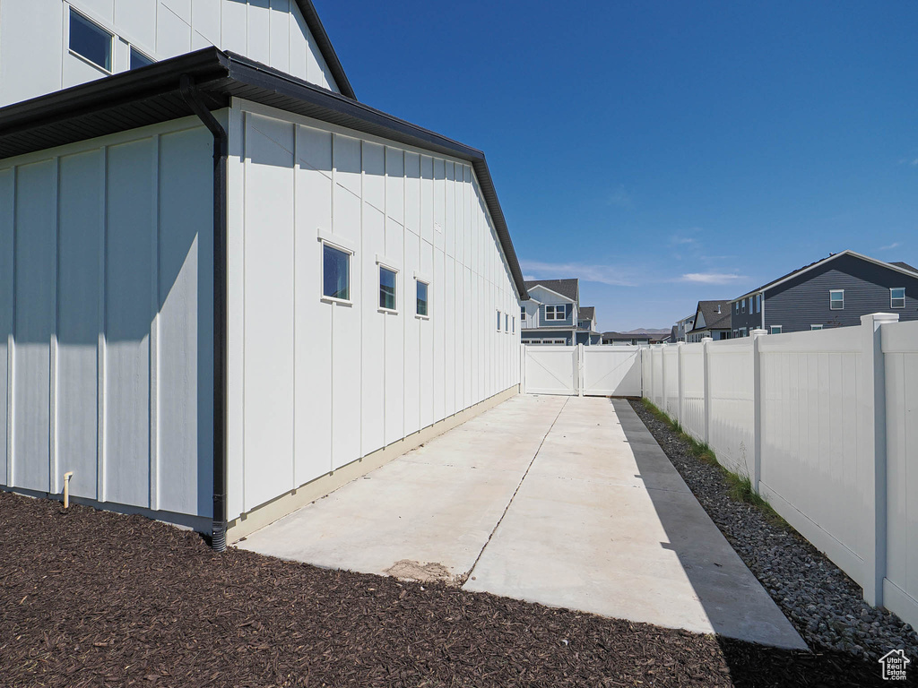 View of property exterior featuring a fenced backyard, board and batten siding, a patio, and a residential view