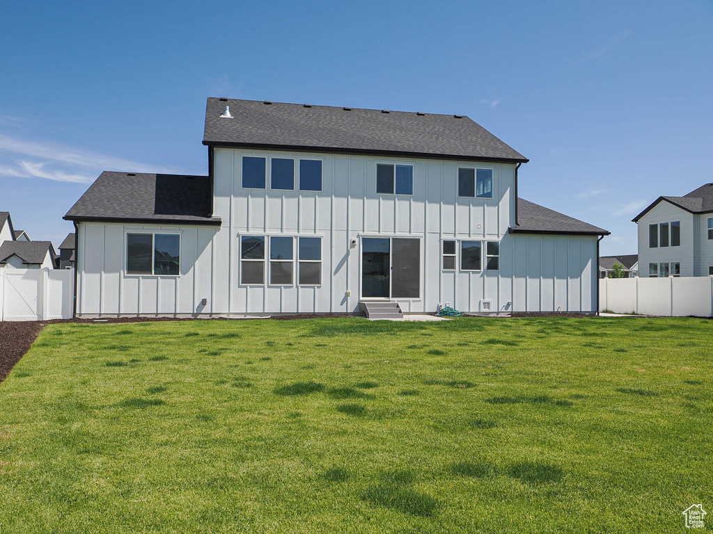 Rear view of house featuring board and batten siding, a fenced backyard, and entry steps