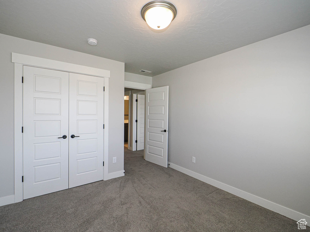 Unfurnished bedroom featuring a closet and carpet floors