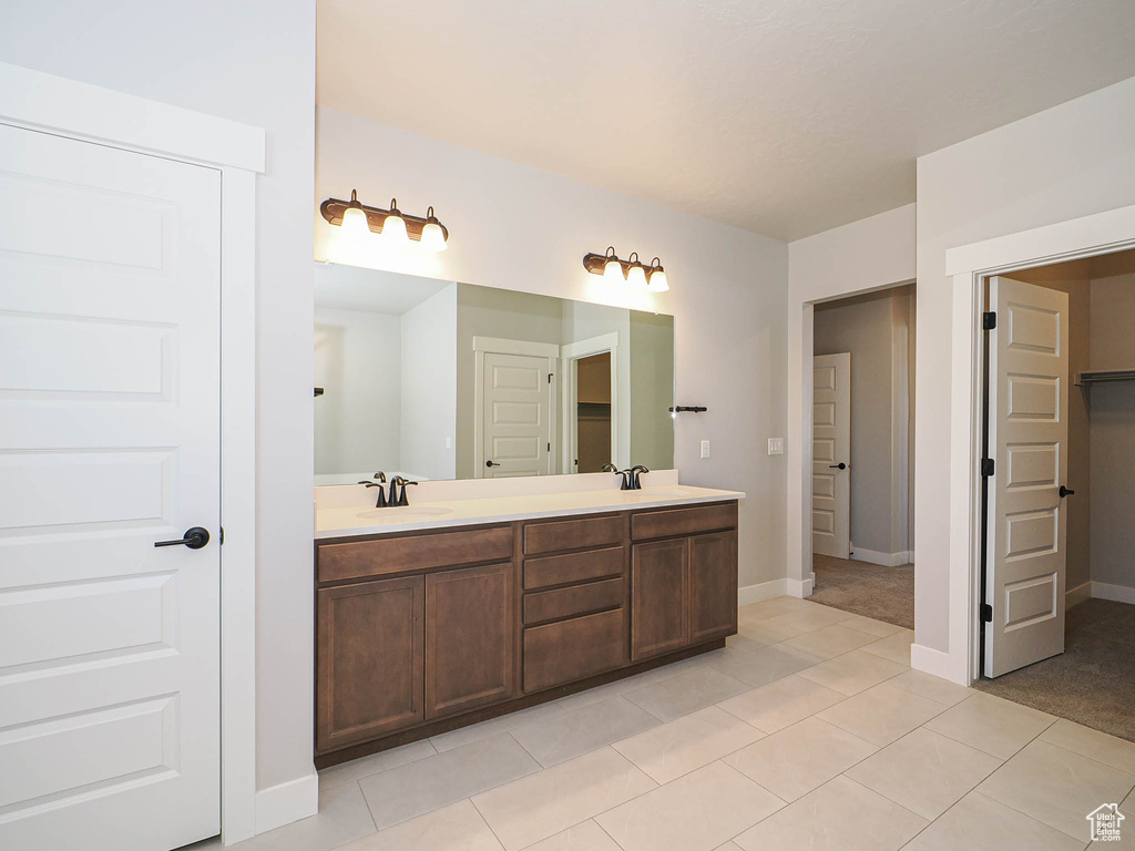 Bathroom featuring a closet, double vanity, and tile patterned floors