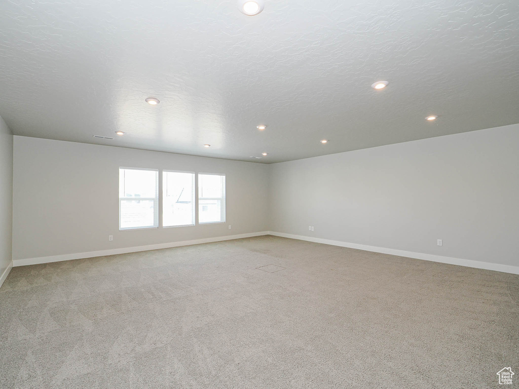 Empty room featuring light carpet, recessed lighting, and a textured ceiling