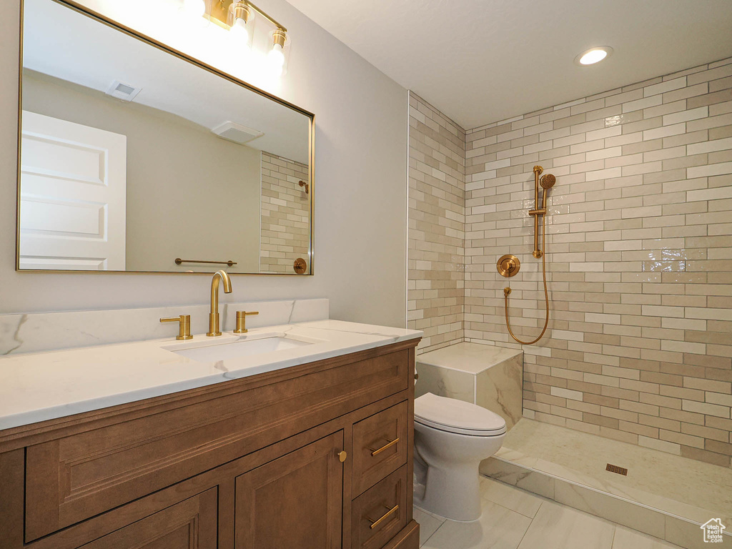 Full bath featuring vanity, tiled shower, and recessed lighting