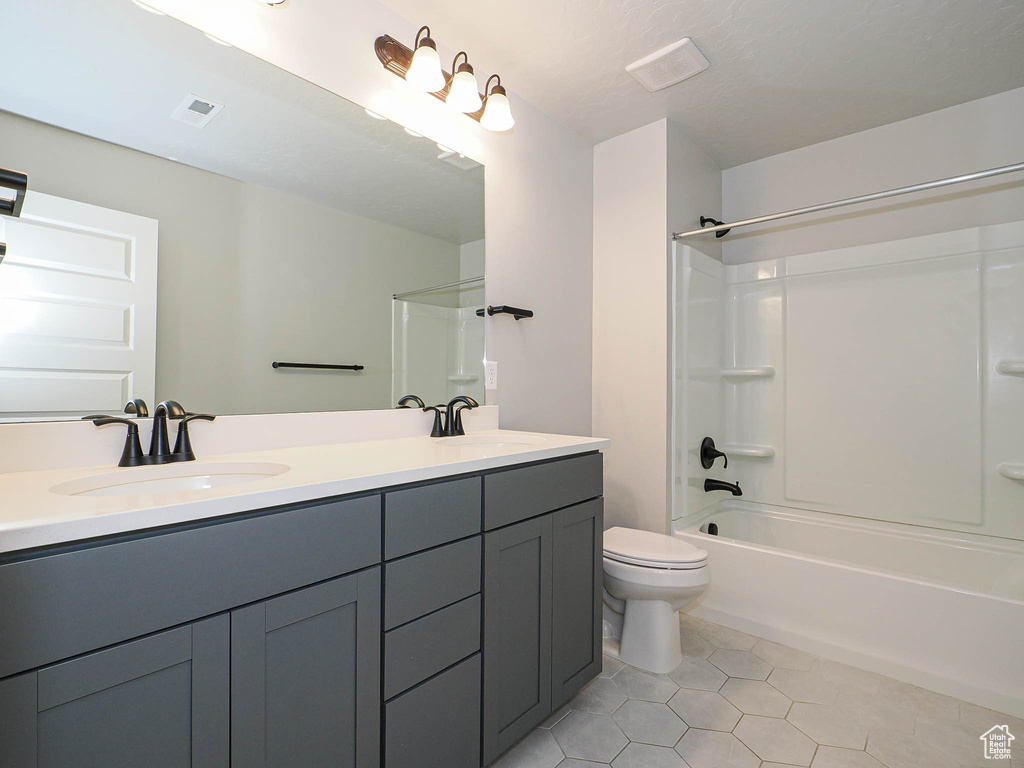 Bathroom featuring double vanity, tile patterned flooring, and tub / shower combination