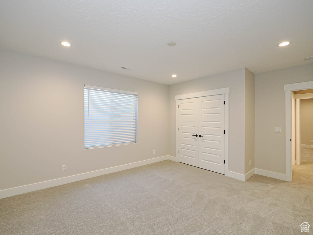 Unfurnished bedroom with recessed lighting, light colored carpet, and a closet